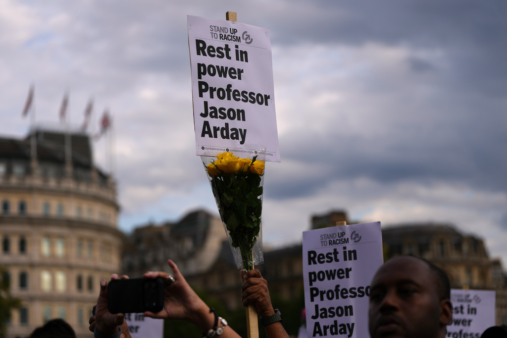 FILE - People attending a vigil held by Stand Up to Racism, in memory of late University of Cambridge professor Jason Arday, hold up signs at Trafalgar Square in London, on Aug. 17, 2026. (AP Photo/Kirsty Wigglesworth, File)