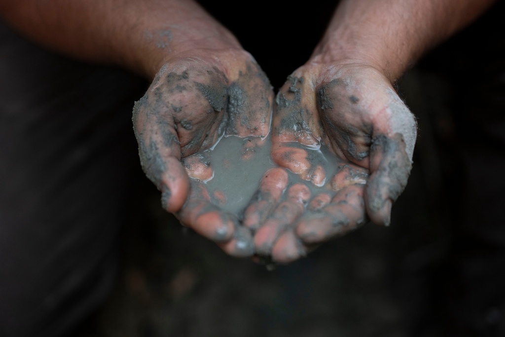 Oszkár Nagyapáti, farmer and member of the volunteer water guardians group, holds water in his hands in Kiskunmajsa, Hungary, Tuesday, July 29, 2025. (AP Photo/Denes Erdos)