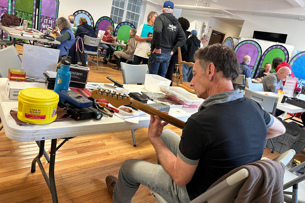 Music repair coach James Dean Conklin helps people fix their instruments at a Repair Cafe in New Paltz, N.Y., May 23, 2026. (AP Photo/Michael Weissenstein)
