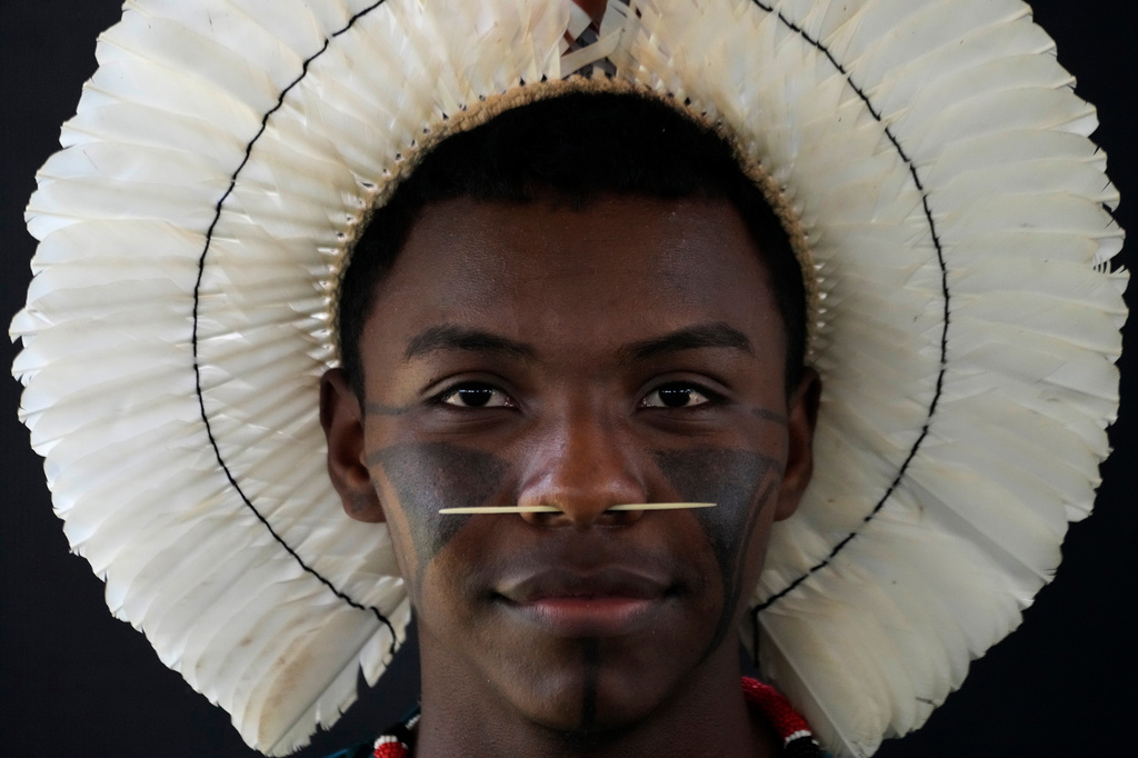 An Indigenous man wearing traditional face paint, feather headdress and piercing poses for a portrait during the opening of the "Acampamento Terra Livre," or Free Land Encampment, Brazil's largest annual Indigenous mobilization that focuses on land rights and environmental protection, in Brasilia, Brazil, Monday, April 6, 2026. (AP Photo/Eraldo Peres)