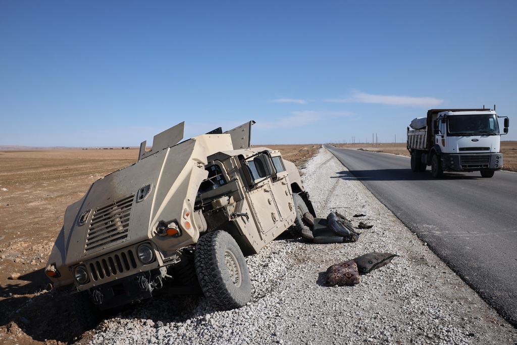 A truck drives past a damaged Humvee abandoned by retreating Syrian Democratic Forces (SDF) along a road between government-controlled Raqqa and SDF-controlled Hassakeh in northeastern Syria, Tuesday, Jan. 20, 2026. (AP Photo/Omar Albam)