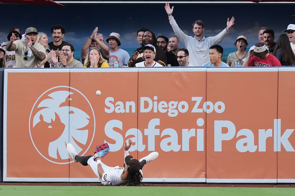 Fans react after San Diego Padres right fielder Fernando Tatis Jr., below, made a catch above the wall for the out on a sacrifice fly by San Francisco Giants' Rafael Devers during the first inning of a baseball game Thursday, July 30, 2026, in San Diego. (AP Photo/Gregory Bull)