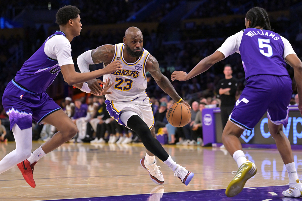 Los Angeles Lakers forward LeBron James (23) is defended by Utah Jazz guard Ace Bailey, left, and Jazz forward Cody Williams as he drives to the basket during the first half of an NBA basketball game Sunday, April 12, 2026, in Los Angeles. (AP Photo/Jayne Kamin-Oncea)
