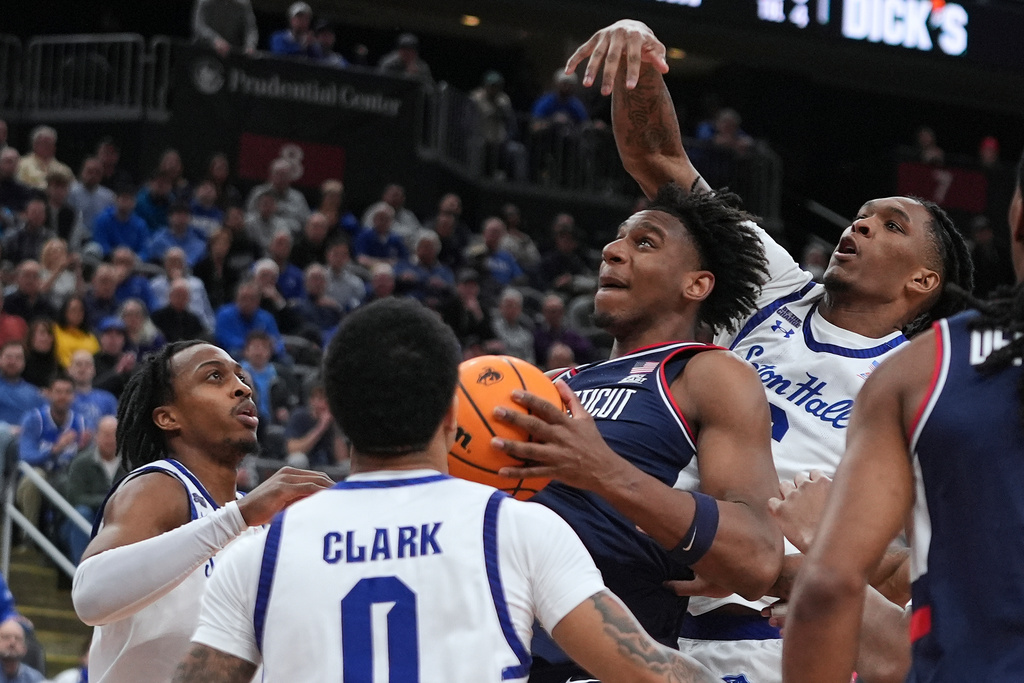 Seton Hall's Stephon Payne III, right, defends a shot by UConn's Tarris Reed Jr., center, during the first half of an NCAA basketball game Tuesday, Jan. 13, 2026, in Newark, N.J. (AP Photo/Frank Franklin II)
