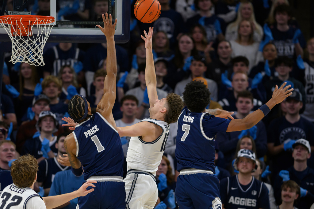 Utah State guard Mason Falslev, center, shoots over Nevada forward Elijah Price, center left, during the first half of an NCAA college basketball game, Wednesday, Jan. 14, 2026, in Logan, Utah. (AP Photo/Tyler Tate)