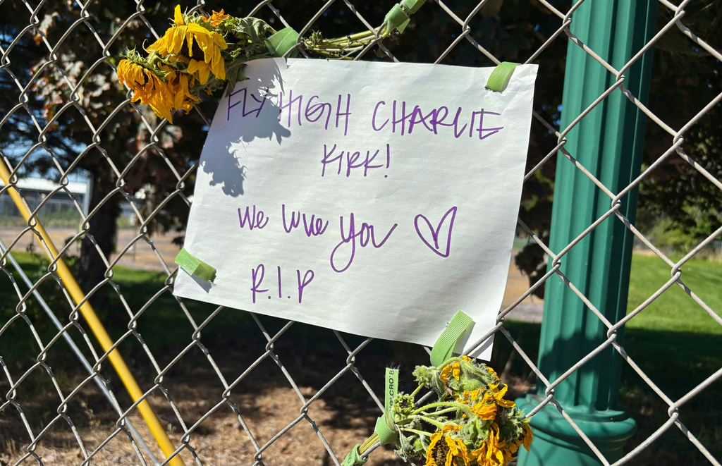 A sign reading “Fly High Charlie Kirk! We love you. R.I.P.” is seen hanging on a fence with flowers across the street from the Utah Valley University campus, in Orem, Utah, Thursday, Sept. 11, 2025. (AP Photo/Hannah Schoenbaum)