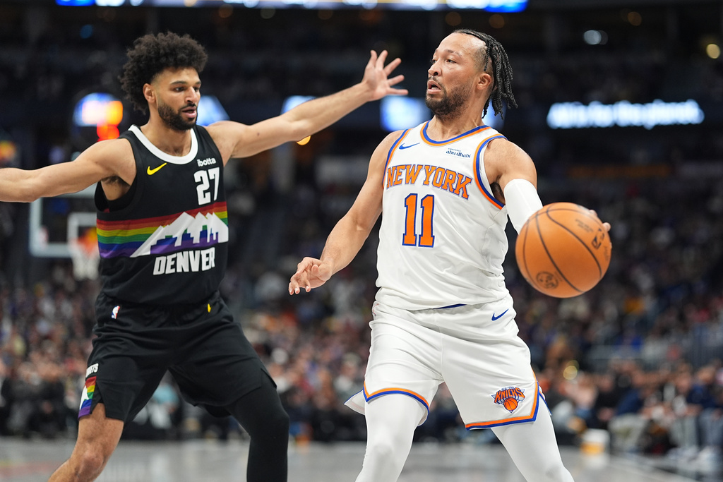 New York Knicks guard Jalen Brunson, right, looks to pass the ball as Denver Nuggets guard Jamal Murray, left, defends in the first half of an NBA basketball game Friday, March 6, 2026, in Denver. (AP Photo/David Zalubowski)