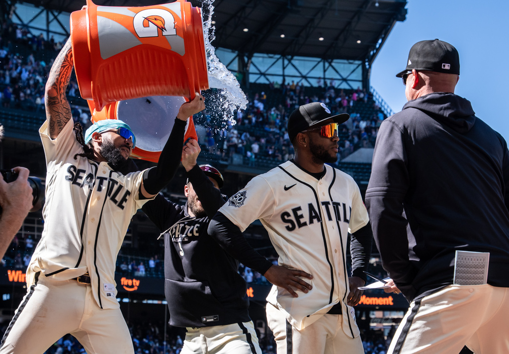 Seattle Mariners' J.P. Crawford, left, douses Victor Robles, second from right, after a baseball game against the Arizona Diamondbacks, Sunday, May 31, 2026, in Seattle. (AP Photo/Stephen Brashear)