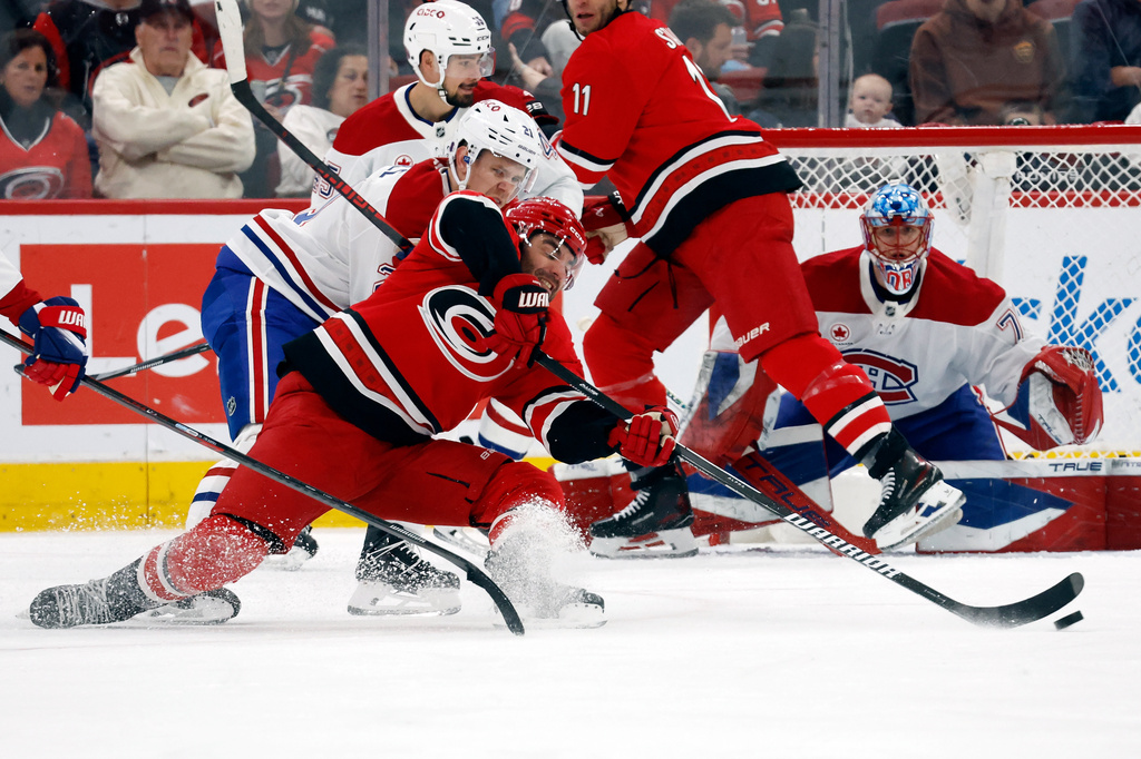Carolina Hurricanes' Jordan Martinook (48) is taken down by Montréal Canadiens' Kaiden Guhle (21) during the first period of an NHL hockey game in Raleigh, N.C., Sunday, March 29, 2026. (AP Photo/Karl DeBlaker)