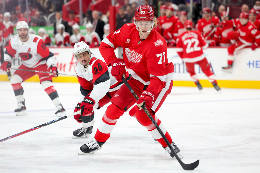 Detroit Red Wings defenseman Simon Edvinsson, right, moves the puck ahead of Carolina Hurricanes center Seth Jarvis during the first period of an NHL hockey game, Monday, Jan. 12, 2026, in Detroit. (AP Photo/Ryan Sun)
