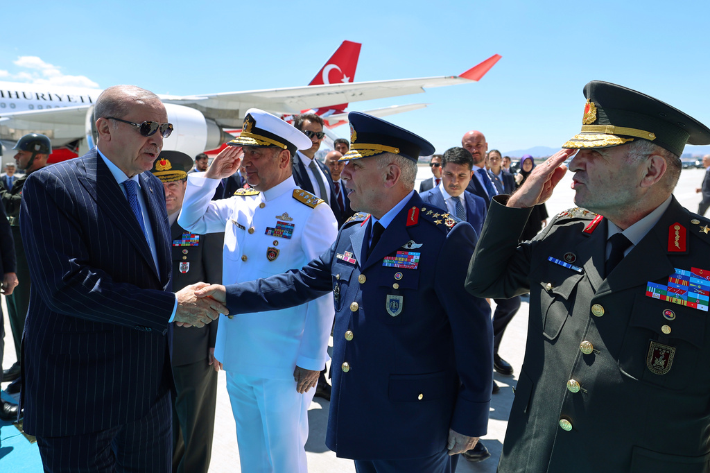 In this handout photo released by Turkish Presidency, Turkish President Recep Tayyip Erdogan, left, greets Turkey's army top commanders during the official opening ceremony of a converted military airport, in Ankara, Monday, June 15, 2025. (Turkish Presidency via AP)