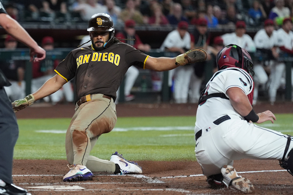 San Diego Padres' Fernando Tatis Jr., left, socres a run ahead of a tag by Arizona Diamondbacks catcher James McCann during the second inning of a baseball game, Tuesday, Aug. 4, 2026, in Phoenix. (AP Photo/Ross D. Franklin)
