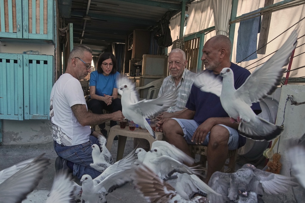 Ibrahim Ammar, left, sits with his wife Loubna Hamdan, his father Salman and a neighbor as they drink tea amid pigeons that they feed on their building's rooftop in Chiyah, the southern suburbs of Beirut, Lebanon, Saturday, July 12, 2025. (AP Photo/Hassan Ammar)