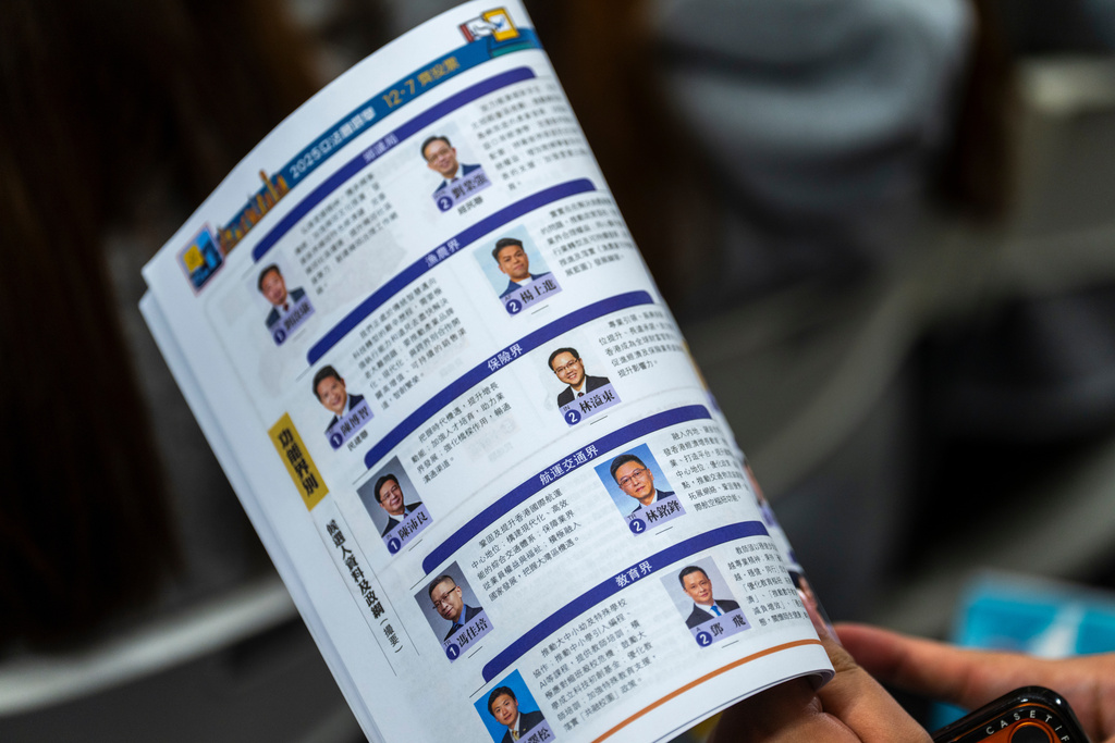 People look at a candidate brochure of the Hong Kong Legislative Council General Election at a forum in Hong Kong on Wednesday, Dec. 3, 2025. (AP Photo/Chan Long Hei)