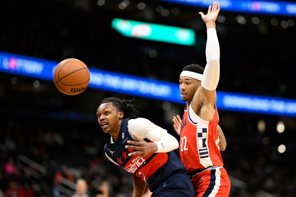 Washington Wizards guard Bub Carrington, left, and Los Angeles Clippers guard Jordan Miller, right, battle for the ball during the first half of an NBA basketball game, Monday, Jan. 19, 2026, in Washington. (AP Photo/Nick Wass)