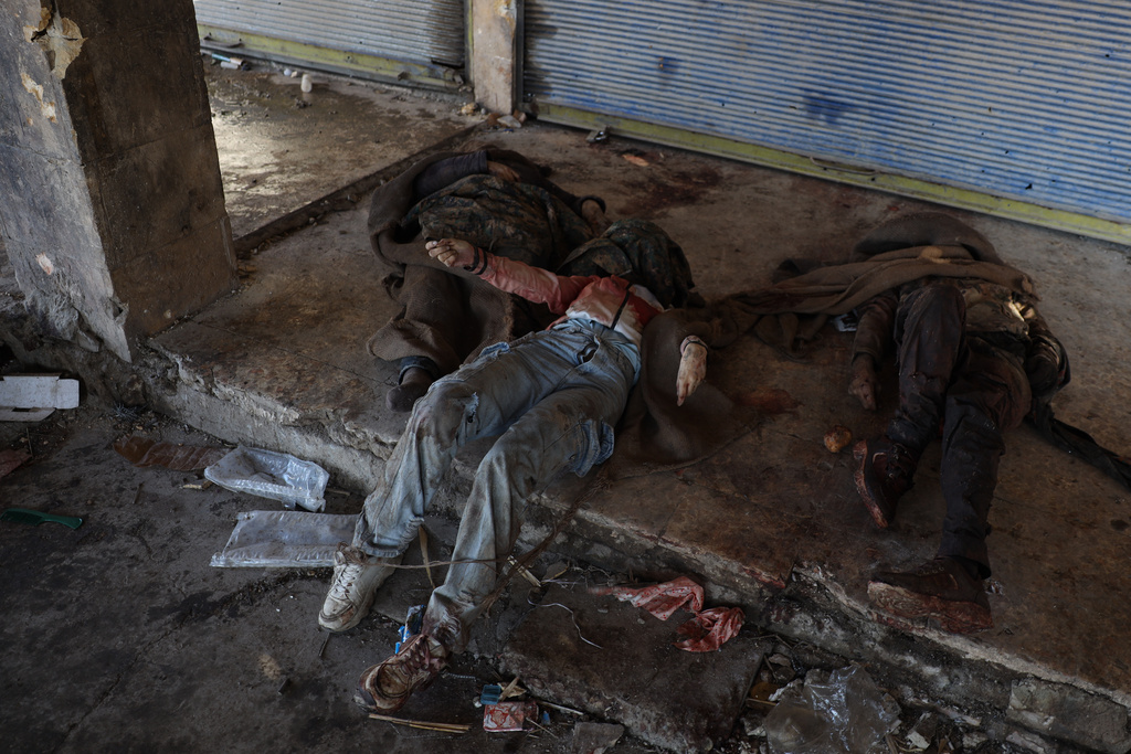EDS NOTE: GRAPHIC CONTENT - Bodies of fighters with the Kurdish-led Syrian Democratic Forces lie on the ground near Al-Aqtan prison on the outskirts of Raqqa, northeastern Syria, Monday, Jan. 19, 2026, after fighting with Syrian government forces. (AP Photo/Omar Albam)