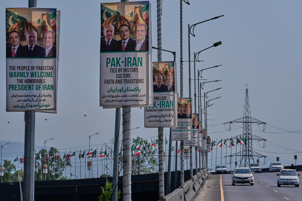 Vehicles drives past welcoming billboards featuring Iranian President Masoud Pezeshkian, right, with Pakistan President Asif Ali Zardari, center, and Shehbaz Sharif alongside an overhead bridge in Islamabad, Pakistan, Tuesday, June 23, 2026. (AP Photo/Anjum Naveed)