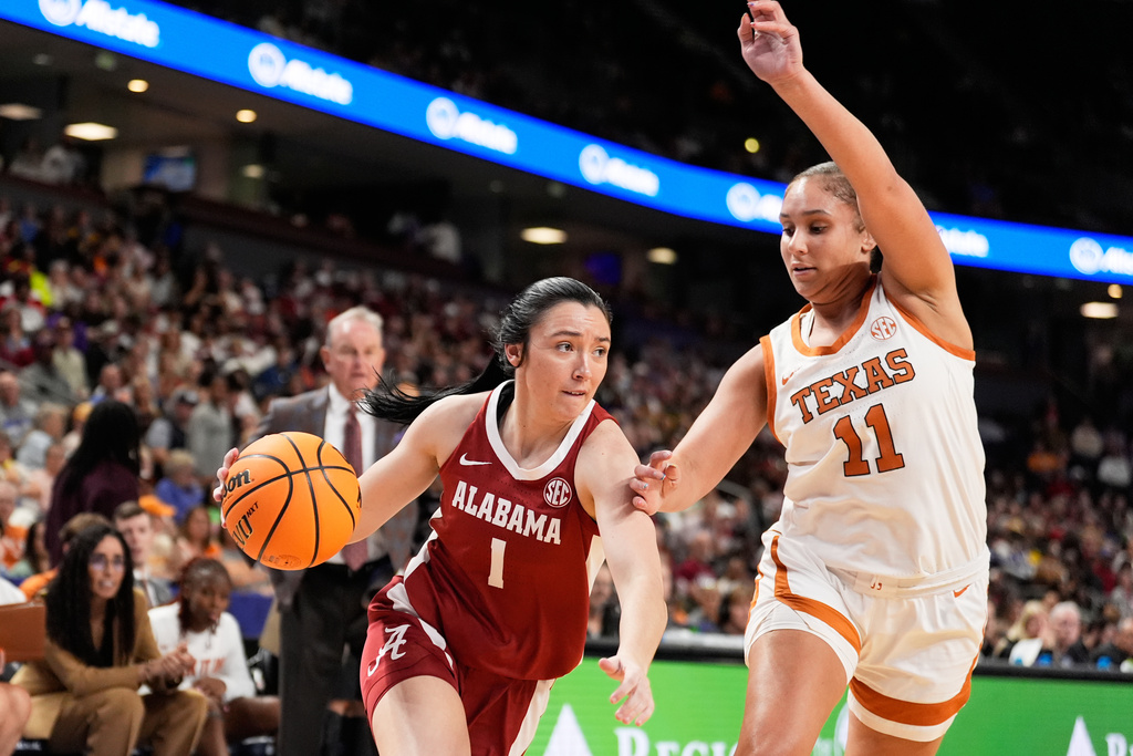 Alabama guard Ace Austin drives to the basket past Texas forward Justice Carlton during first half of an NCAA college basketball game in the quarterfinals of the Southeastern Conference tournament, Friday, March 6, 2026, in Greenville, S.C. (AP Photo/Chris Carlson)