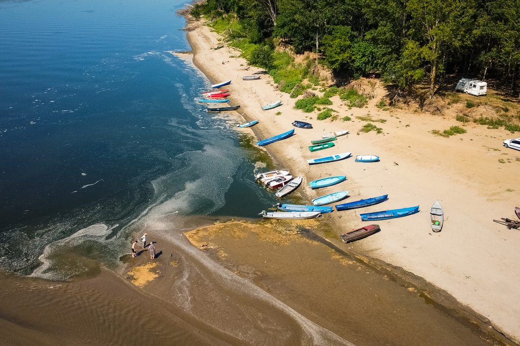 People stand on a bank of sand on the Danube River as usually submerged areas are exposed due to extreme low levels of the water following an extended period of drought in Corabia, Romania, Wednesday, July 29, 2026. (AP Photo/Nicolae Dumitrache)