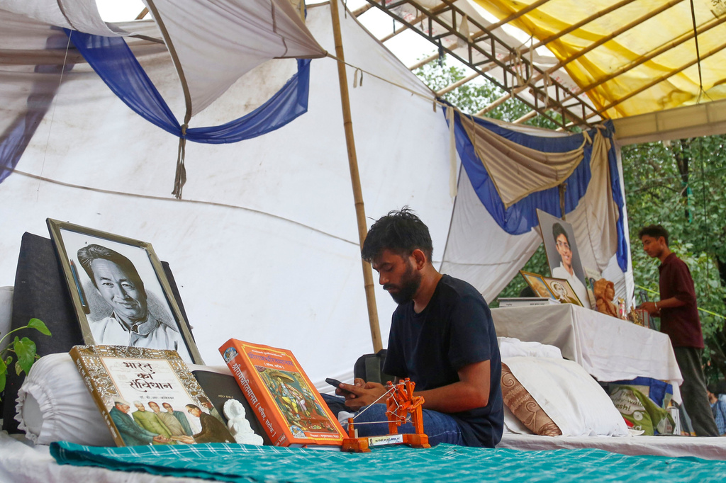 Abhijeet Dipke, founder of the Cockroach Janta Party, sits by a portrait of hunger-striking activist Sonam Wangchuk during a protest in New Delhi, Tuesday, July 21, 2026. (AP Photo/Shekhar Yadav)