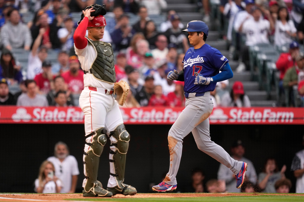 Los Angeles Dodgers' Shohei Ohtani, right, scores on a sacrifice fly by Will Smith as Los Angeles Angels catcher Logan O'Hoppe stands at the plate during the first inning of a baseball game Saturday, May 16, 2026, in Anaheim, Calif. (AP Photo/Mark J. Terrill)