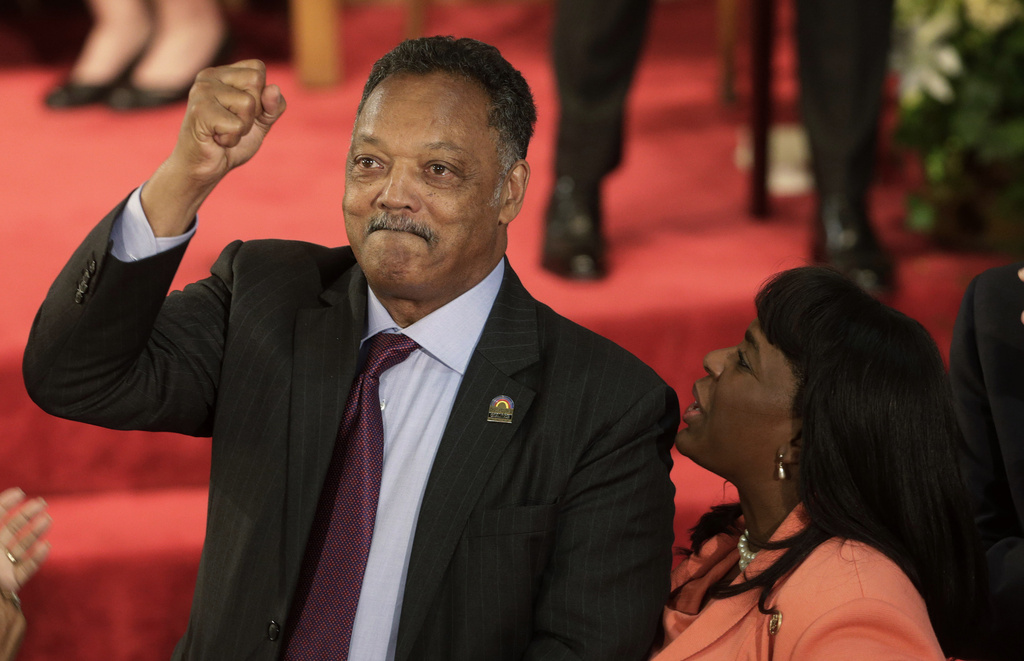 FILE - Rev. Jesse Jackson gestures to a friend in the balcony at the 16th Street Baptist Church in Birmingham, Ala., Sept. 15, 2013. The church held a ceremony honoring the memory of the four young girls who were killed by a bomb placed outside the church 50 years ago by members of the Ku Klux Klan. At right is U.S. Rep. Terri Sewell, D-Ala. (AP Photo/Dave Martin, File)