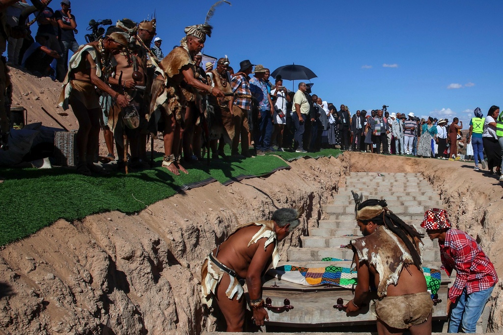 In this photo provided by the South African Government Communications and Information Services, Men lower a coffin into the grave during a reburial of remains of dozens of Africans whose bodies were dug up and sent to Europe for scientific research long ago, in Steinkopf, South Africa, Monday, March 23, 2026. (Jairus Mmutle/GCIS via AP)