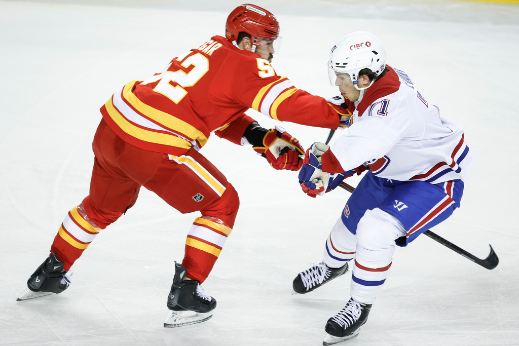 Montreal Canadiens' Jake Evans, right, is checked by Calgary Flames' MacKenzie Weegar during second period NHL hockey action in Calgary on Wednesday, Oct. 22, 2025. (Jeff McIntosh/The Canadian Press via AP)