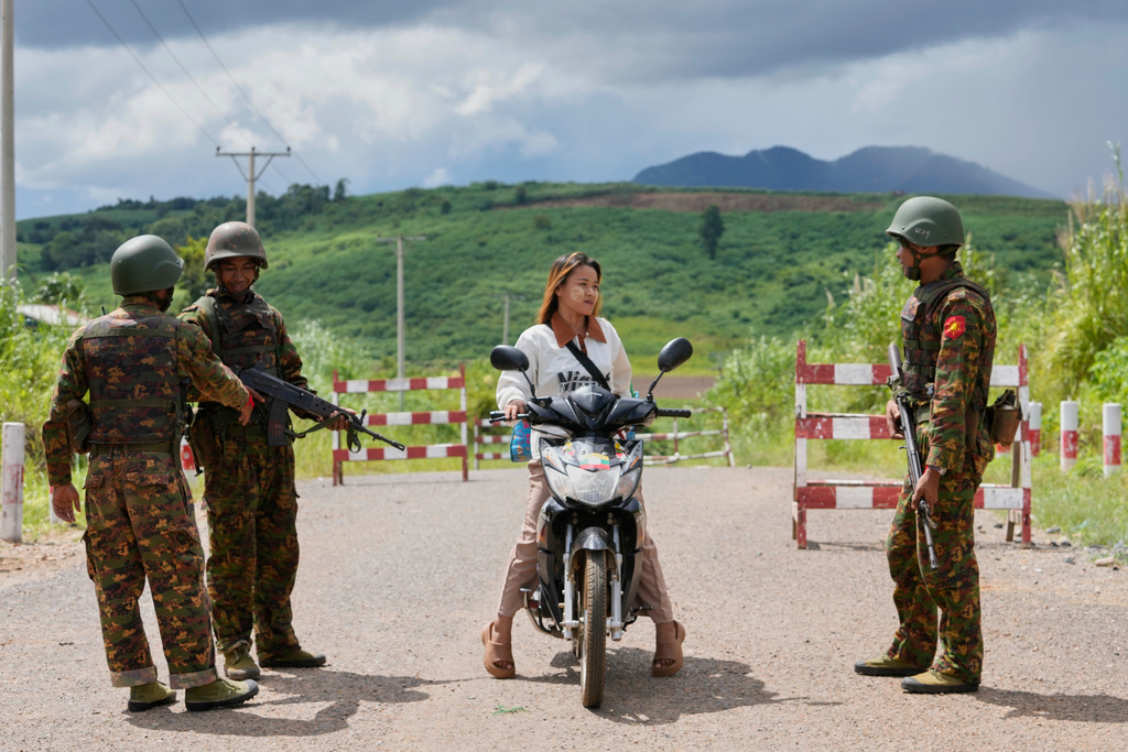 In this photo taken during a trip supervised by pro-military Myanmar media, soldiers stop a motorcyclist at a check point in Kyaukme, northern Shan State, Myanmar, Friday, Oct. 10, 2025. (AP Photo/Aung Shine Oo)