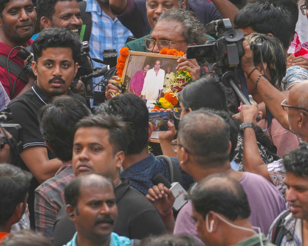 A fan holds the photograph of Bollywood actor Dharmendra during his funeral outside a cremation center in Mumbai India, Monday, Nov. 24, 2025.(AP Photo/Rafiq Maqbool)