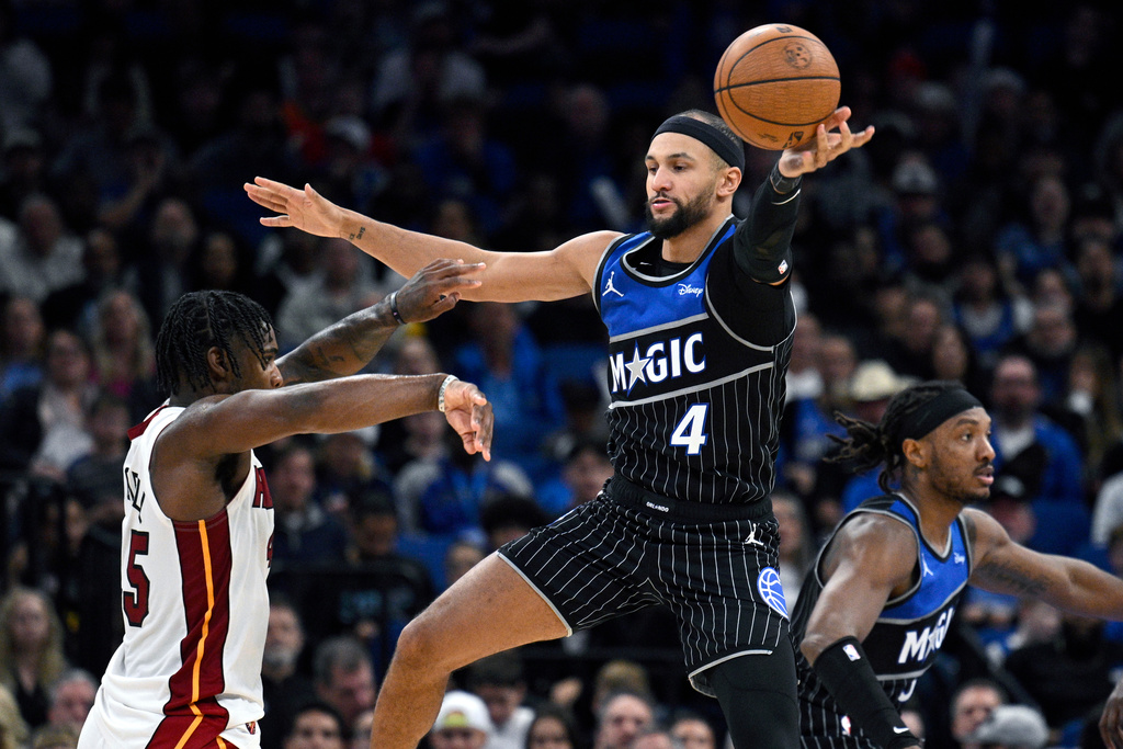 Orlando Magic guard Jalen Suggs (4) deflects a pass by Miami Heat guard Davion Mitchell, left, during the second half of an NBA Cup basketball game, Tuesday, Dec. 9, 2025, in Orlando, Fla. (AP Photo/Phelan M. Ebenhack)