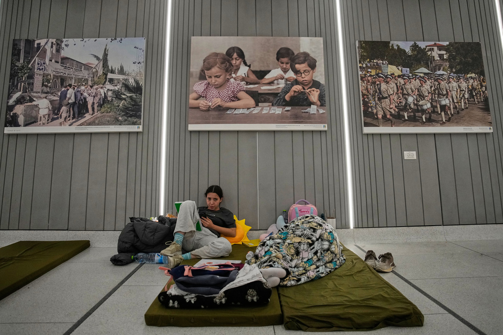 People take shelter in an underground metro station as air raid sirens warn of incoming Iranian missiles in Tel Aviv, Israel, Saturday, March 7, 2026. (AP Photo/Ohad Zwigenberg)