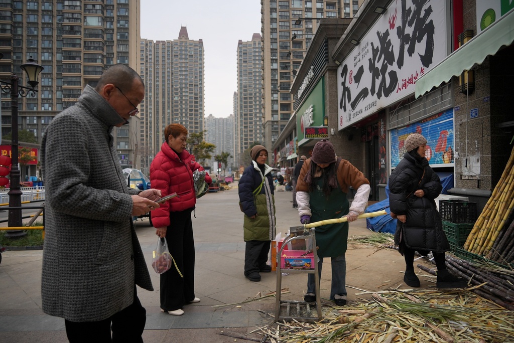 A shopkeeper cuts sugar cane for juicing at the semi-abandoned "Life in Venice" housing complex in Qidong, on China's east coast, Feb. 5, 2026. (AP Photo/Dake Kang)