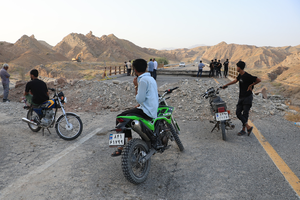 People stand on a bridge destroyed after a strike in Hormozgan province, southern Iran, Saturday, July 18, 2026. (Amirhosein Khorgooi/Iranian Students' News Agency via AP)