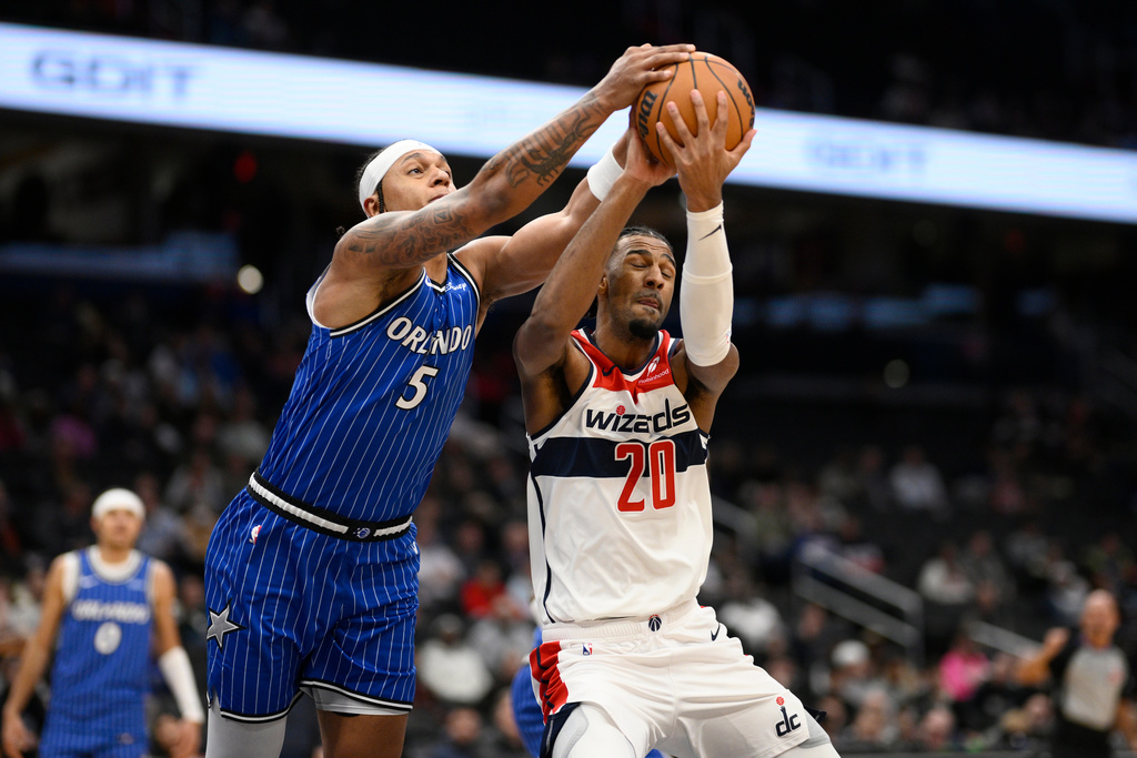 Orlando Magic forward Paolo Banchero (5) and Washington Wizards center Alex Sarr (20) battle for the ball during the first half of an NBA basketball game, Tuesday, Jan. 6, 2026, in Washington. (AP Photo/Nick Wass)
