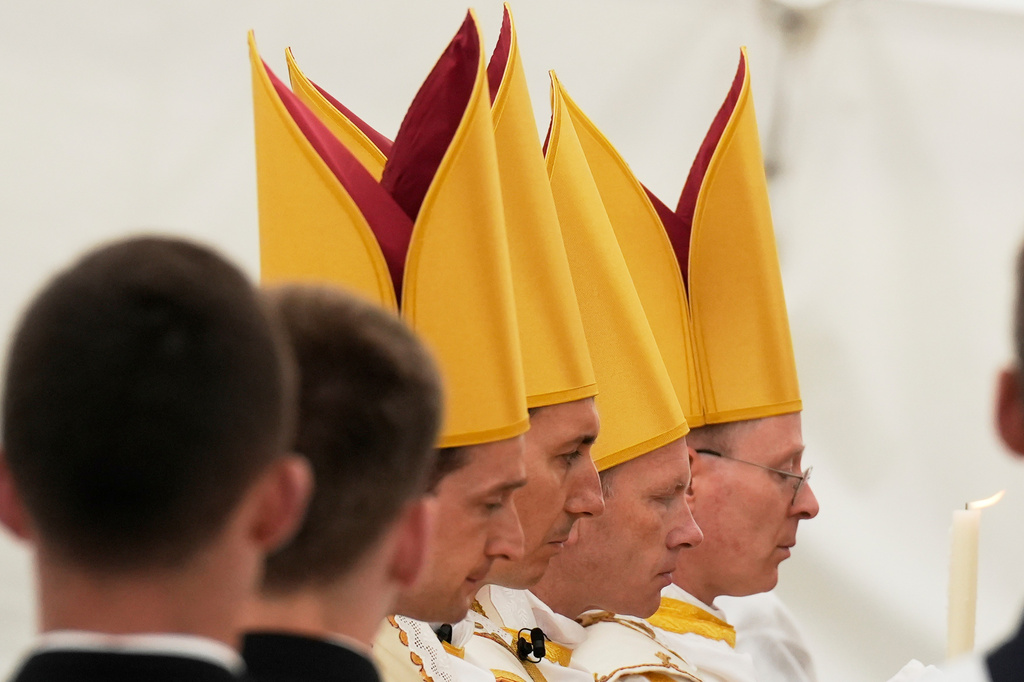 Newly consecrated bishops, from left, Marc Hanappier, Michel Poinsinet de Sivry, Michael Goldade and Pascal Schreiber, wearing their miters pray at the end of their consecration ceremony in a tent set up outside the Society of St. Pius X seminary in Econe, Switzerland, Wednesday, July 1, 2026. (AP Photo/Baz Ratner)