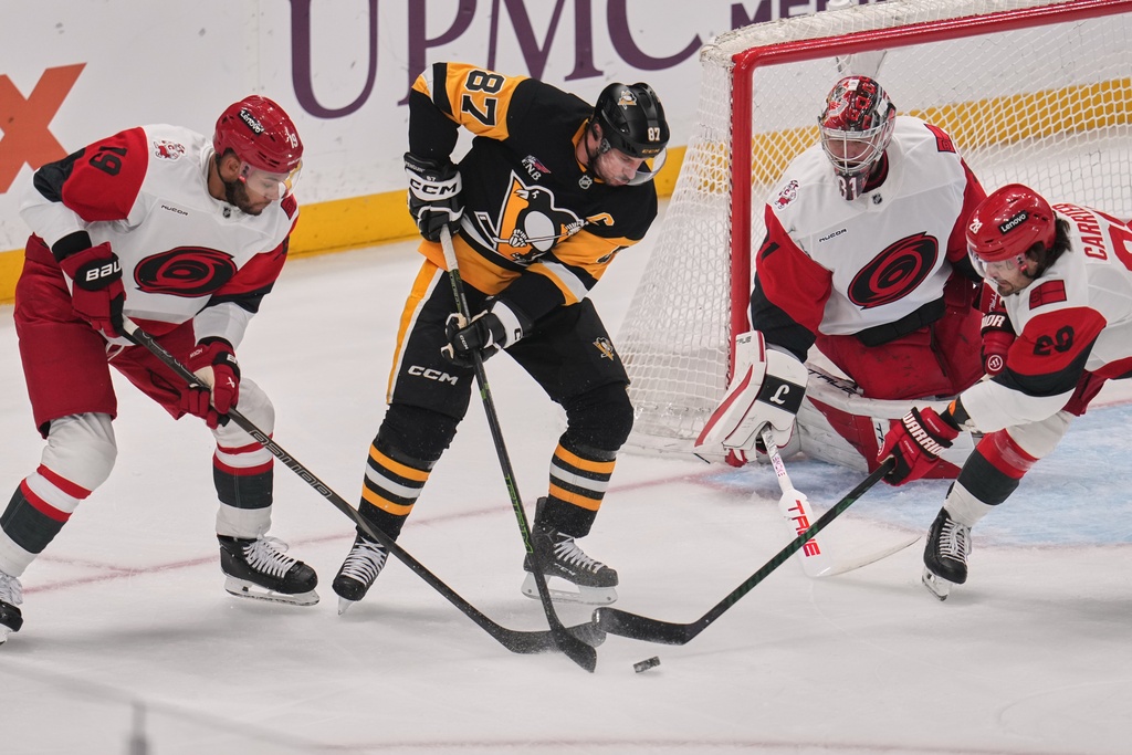 Pittsburgh Penguins' Sidney Crosby (87) is defended by Carolina Hurricanes' K'andre Miller (19) and William Carrier (28) in front of goalie Frederik Andersen, second from right, during the first period of an NHL hockey game in Pittsburgh, Sunday, March 22, 2026. (AP Photo/Gene J. Puskar)