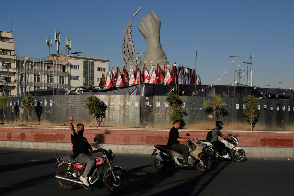 A man reacts to the camera while driving past a monument depicting the clenched fist of the late Iranian Supreme Leader Ayatollah Ali Khamenei, who was killed in the U.S. and Israel strike on Feb. 28, and a missile at the Islamic Revolution square in downtown Tehran, Iran, Tuesday, Sept. 15, 2026. (AP Photo/Vahid Salemi)