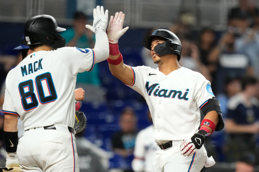 Miami Marlins' Heriberto Hernández, right, is met by Joe Mack (80) after hitting a solo home run during the second inning of a baseball game against the Texas Rangers, Tuesday, June 23, 2026, in Miami. (AP Photo/Lynne Sladky)
