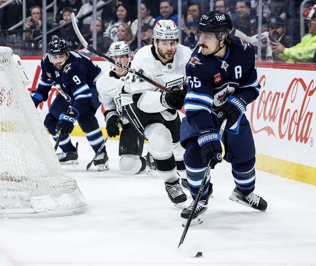 Winnipeg Jets' Mark Scheifele (55) looks to pass the puck with Los Angeles Kings' Alex Laferriere (14) in pursuit during second-period NHL hockey game action in Winnipeg, Manitoba, Friday, Jan. 9, 2026. (John Woods/The Canadian Press via AP)