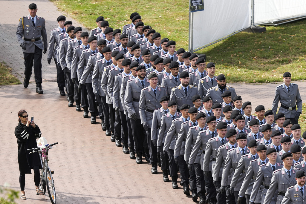 A woman takes pictures of new recruits of the German Army Bundeswehr who are going to attend a ceremony to take their oath in front of the North Rhine-Westphalia state parliament in Duesseldorf, Germany, Thursday, Sept. 4, 2025. (AP Photo/Martin Meissner)