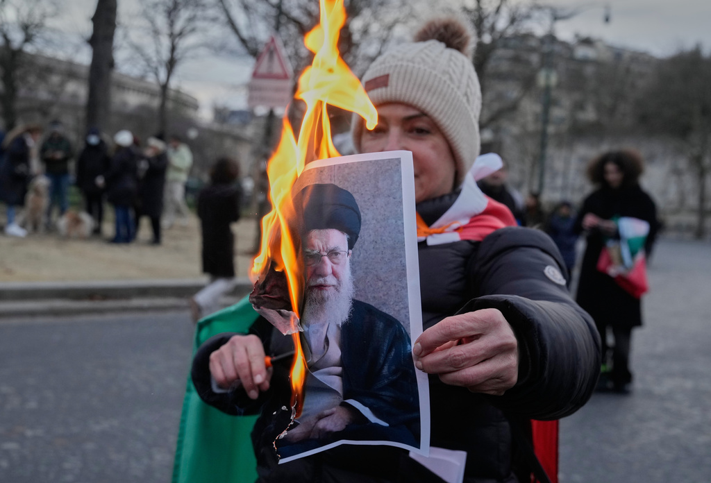 A protester holds a burning poster of Iran's Supreme Leader Ayatollah Ali Khamenei during a rally in support of the nationwide mass demonstrations in Iran against the government, Sunday, Jan. 11, 2026, in Paris. (AP Photo/Michel Euler)