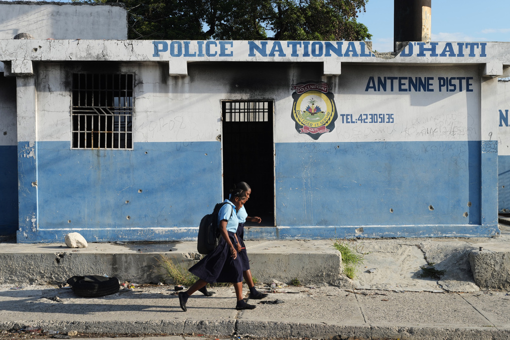 Students walk past a police station that was set on fire by armed gangs in the Carrefour Aeoport area of the Delmas neighborhood of Port-au-Prince, Haiti, Tuesday, Feb. 24, 2026. (AP Photo/Odelyn Joseph)
