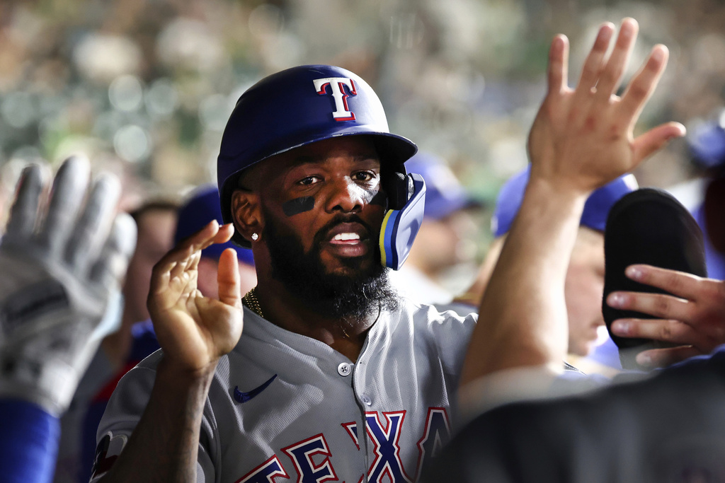 Texas Rangers' Adolis García celebrates in the dugout after scoring during the ninth inning of a baseball game against the Athletics Saturday, Aug. 30, 2025, in West Sacramento, Calif. (AP Photo/Sara Nevis)