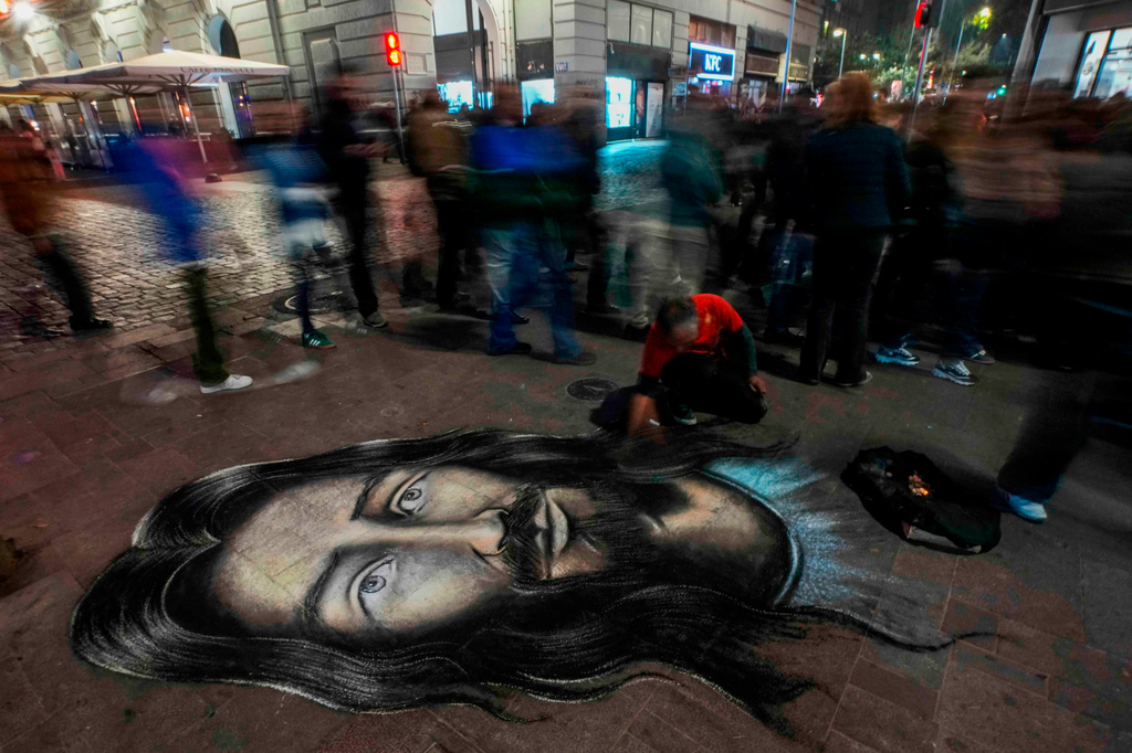 FILE - Street artist Mauro Maureira paints an image of Jesus Christ as faithful take part in the Christ of May procession in Santiago, Chile, May 13, 2026. (AP Photo/Esteban Felix, File)