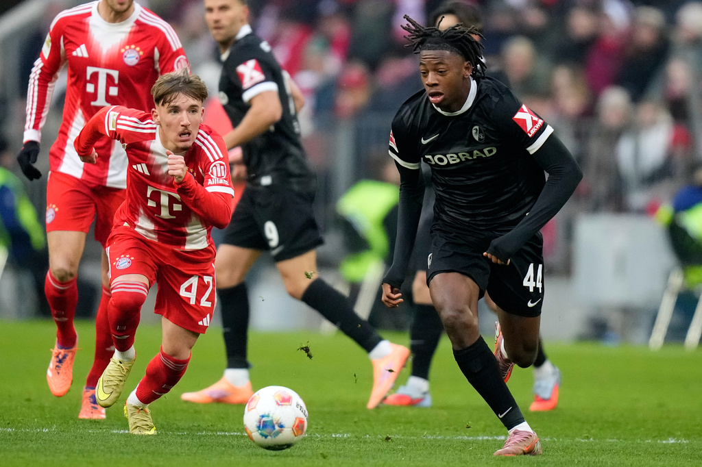 Bayern's Lennart Karl, left, and Freiburg's Johan Manzambi challenge for the ball during the Bundesliga soccer match between Bayern Munich and Freiburg in Munich, Germany, Saturday, Nov. 22, 2025.(AP Photo/Matthias Schrader)