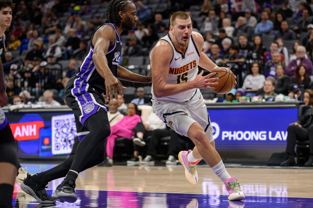 Denver Nuggets center Nikola Jokic (15) drives past Sacramento Kings forward Precious Achiuwa during the first half of an NBA basketball game in Sacramento, Calif., Thursday, Dec. 11, 2025. (AP Photo/Randall Benton)