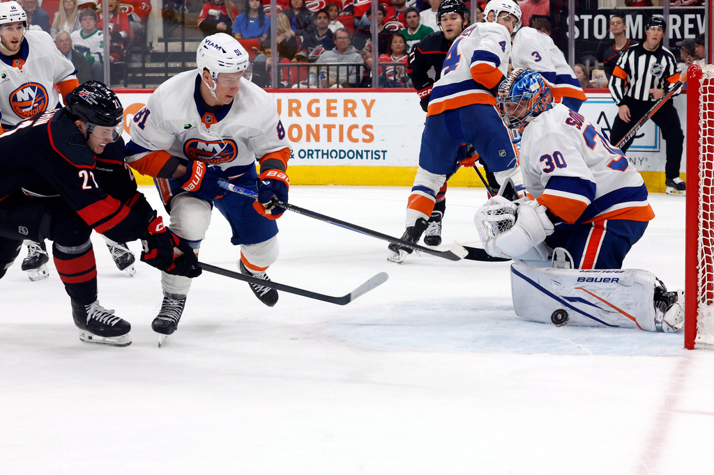 Carolina Hurricanes' Alexander Nikishin (21) has his shot go off the pad of New York Islanders goaltender Ilya Sorokin (30) with Ondrej Palat (81) nearby during the second period of an NHL hockey game in Raleigh, N.C., Saturday, April 4, 2026. (AP Photo/Karl DeBlaker)