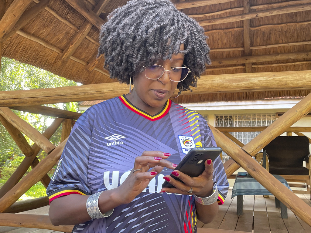 Radio host Siima Kyakuhaire Sabiti scrolls her phone looking for old pictures of her with New York Mayor-elect Zohran Mamdani during his 2019 visit to her show in Kampala, Uganda. Wednesday, Nov. 5, 2025. (AP Photo/Hajarah Nalwadda)