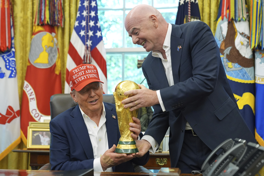 FIFA President Gianni Infantino, right, hands the FIFA World Cup Winners Trophy to President Donald Trump during an announcement in the Oval Office of the White House, Friday, Aug. 22, 2025, in Washington. (AP Photo/Jacquelyn Martin)
